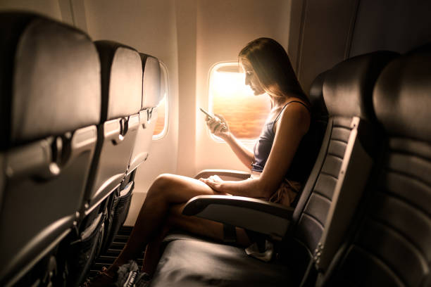 mujer con teléfono inteligente en el asiento del avión - telephone cabin fotografías e imágenes de stock