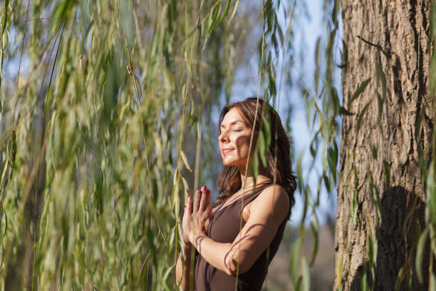 yoga-meditation pose unter den weidenbaumzweigen - frau weide stock-fotos und bilder