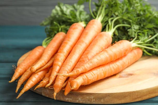istock Cutting board with ripe carrots on wooden table 1135616617