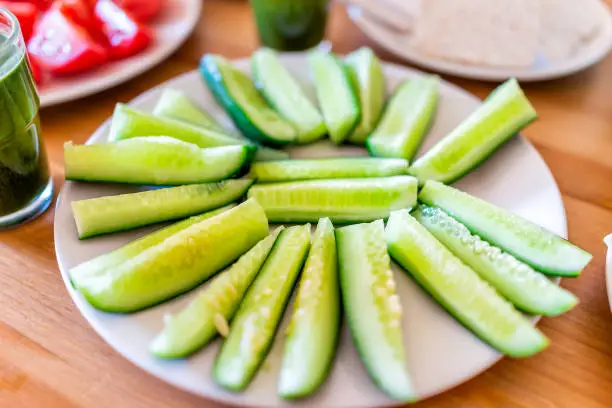 Fresh sliced juicy ripe cucumbers slices on plate closeup on wooden table as healthy snack or salad appetizer