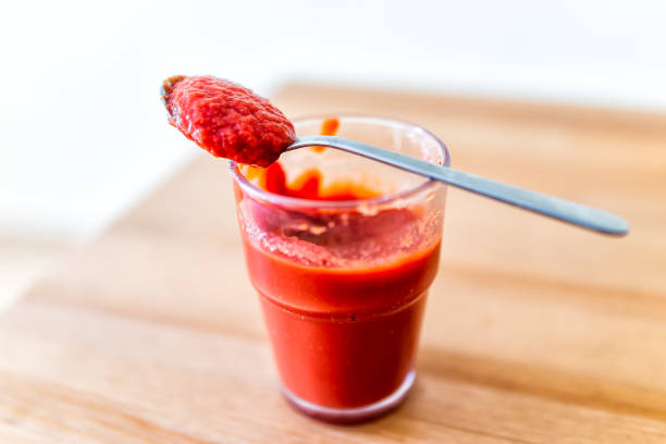 nahaufnahme von glas mit tomatenmark oder sauce in löffel isoliert auf holztisch mit bokeh rücken und rot lebendige frische farbe - vibrant color tomato vegetable pasta stock-fotos und bilder