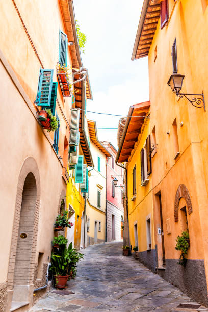 chiusi, italia callejón en la calle en el pequeño pueblo histórico de la ciudad medieval en umbría vista vertical durante el día soleado con naranja amarillo brillante vibrante paredes coloridas - narrow alley fotografías e imágenes de stock