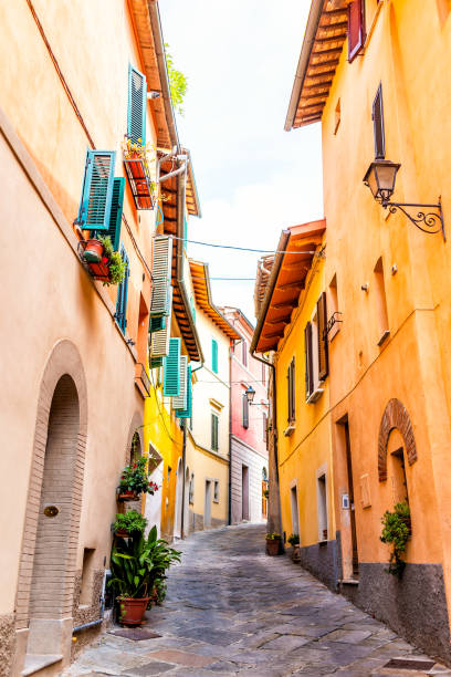 chiusi, italy street alley in small historic medieval town village in umbria vertical view during sunny day with orange yellow bright vibrant colorful walls - sunny apartment window sky imagens e fotografias de stock