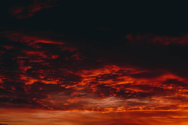 Fiery red blood vampire dawn. Amazing warm dramatic fire cloudy sky. Vivid orange sunlight. Atmospheric background of sunrise in overcast weather. Hard cloudiness. Storm clouds warning. Copy space.