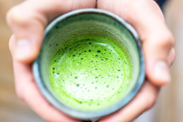 Macro flat top closeup of man person hands holding tea cup bokeh background in garden drinking matcha green drink in spring or autumn season Macro flat top closeup of man person hands holding tea cup bokeh background in garden drinking matcha green drink in spring or autumn season gifu prefecture stock pictures, royalty-free photos & images