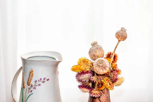 Dry flowers arrangement bouquet of gerbera daisies by vase brown vintage yellow red colors by house window with retro sunlight