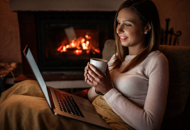 istock Woman using laptop near fireplace 1135637497