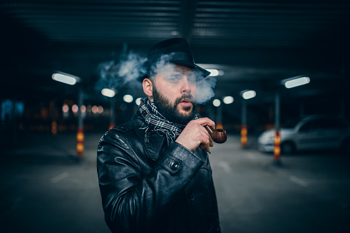 Bearded man with a hat using smoking pipe