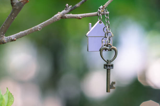 istock Home key with house keyring hanging with green garden background, copy space 1135642864