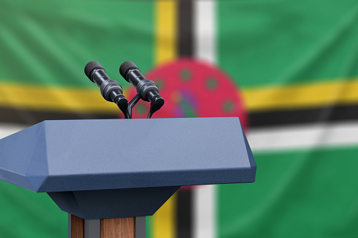 Podium lectern with two microphones and Dominica flag in background