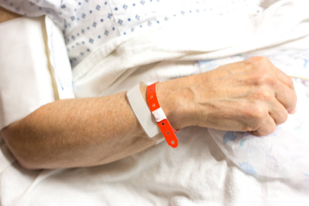 letto d'ospedale: uomo con braccialetti identificati, monitoraggio della pressione sanguigna - braccialetto di identificazione foto e immagini stock