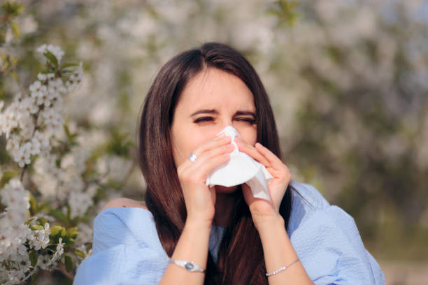 istock Allergic Woman Blowing Her Nose Next to Blooming Tree 1135651360