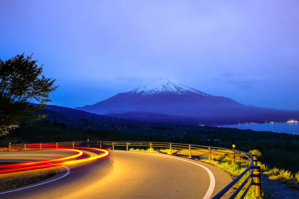 istock Light trails on mountain street on Fuji mountain light blue background in twilight, the light from car turn on during drive on the road in sunset time, light trails on road so colorful in Japan. 1135652410