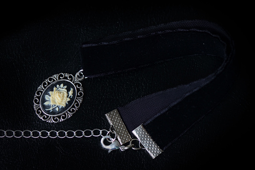 Black velvet choker with rose cameo on a dark background close up