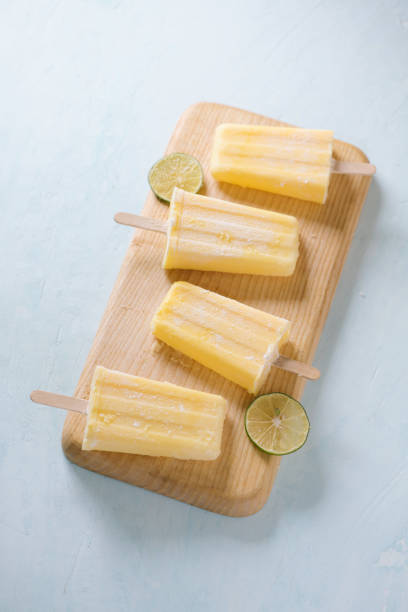 istock Pineapple popsicles on a marble paddle board. Top view over a blue wood background. 1135666472