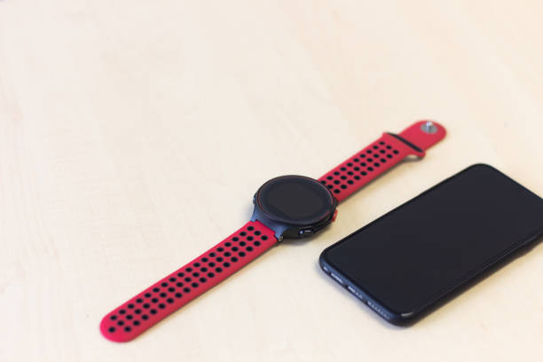 istock Red smart watch  and black smart mobile phone on wooden table. 1135672047