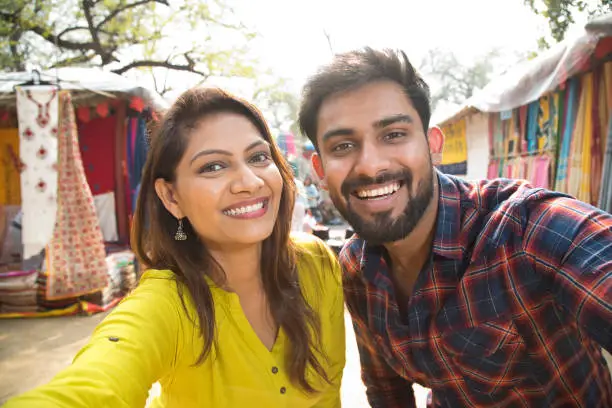 Happy Indian couple taking selfie at street market