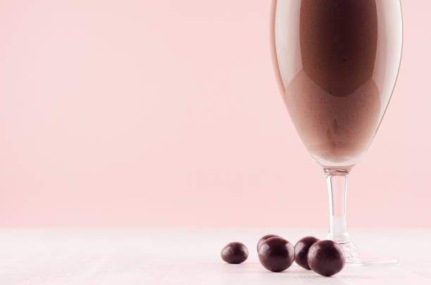 istock Fresh chocolate milkshake with chocolate candy balls in gentle graceful soft pink interior, detail, closeup. 1135672240