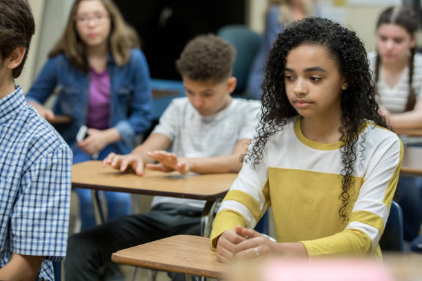 vielfältige gruppe von gymnasiasten im teenageralter, die während der haft am schreibtisch sitzen, gelangweilt und depressiv aussahen - hängebrücke stock-fotos und bilder