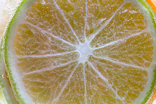 Slice of lime in the water with bubbles close up.