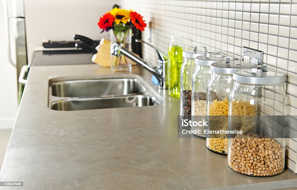 Kitchen sink and countertop with glass jars of food Modern small kitchen interior with glass jars on natural stone countertop Kitchen Counter Stock Photo