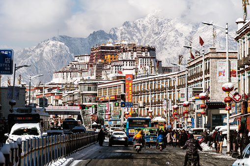 Lhasa, China - December 19 2018: Traffic in the Lhasa old town after an snow fall in winter with the Potala Palace in the background in Tibet.
