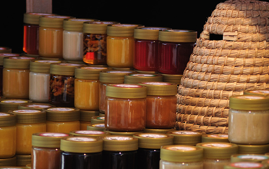 market stall with honey in glass jars, decorated with basket bee hive