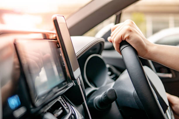 istock Male driver hand holding on steering wheel using smartphone for GPS navigation. Mobile phone mounting with magnet on the car console in modern car. Urban driving lifestyle with mobile app technology 1135678340