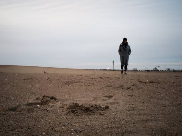 istock lonely woman on an empty beach in winter 1135684091