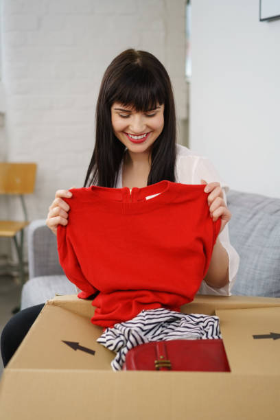 istock Young woman smiling as she unpacks a gift 1135692019