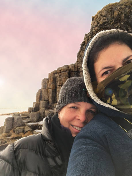 Mature sisters taking a selfie in front of Dverghamrer, Southern Iceland. The sun is going down in the background.