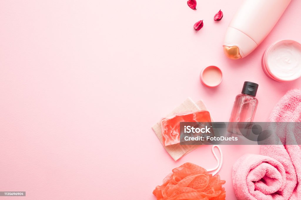 Pots de crème, bouteille de douche, huile essentielle, serviette, WISP orange et savon sur table rose pastel. Produits relax pour le lavage du corps. Endroit vide pour le texte, citation, dictons ou logo. - Photo de Rose libre de droits