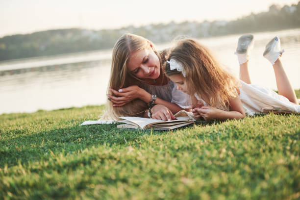 istock mother with a child reads a book on the grass 1135697522
