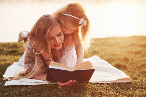istock mother with a child reads a book on the grass 1135697667