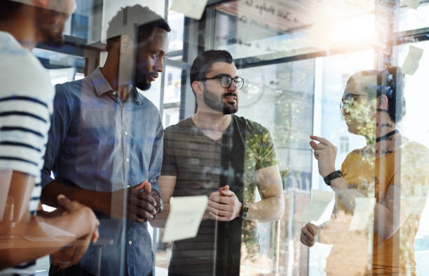 Let’s try it this way for a change Shot of a group of young designers brainstorming with notes on a glass wall in an office transparent wipe board stock pictures, royalty-free photos & images