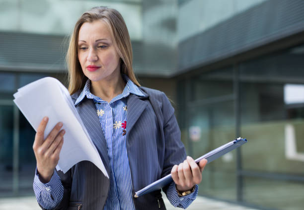 istock Employee  woman standing with folder of documents 1135699097