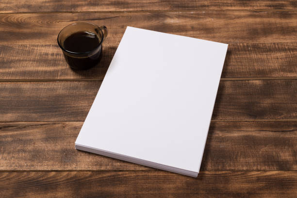 istock Blank paper notebook on brown wooden table background. Top view with copy space 1135703217