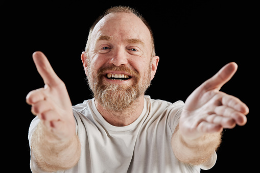Smiling mature man with his arms out in welcome