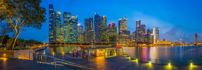 The glittering lights of Downtown Core skyscrapers reflecting in the tranquil waters of Marina Bay in the heart of Singapore.