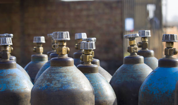 row of liquefied oxygen industrial gas containers with valves. close up of valves - botija de gas imagens e fotografias de stock