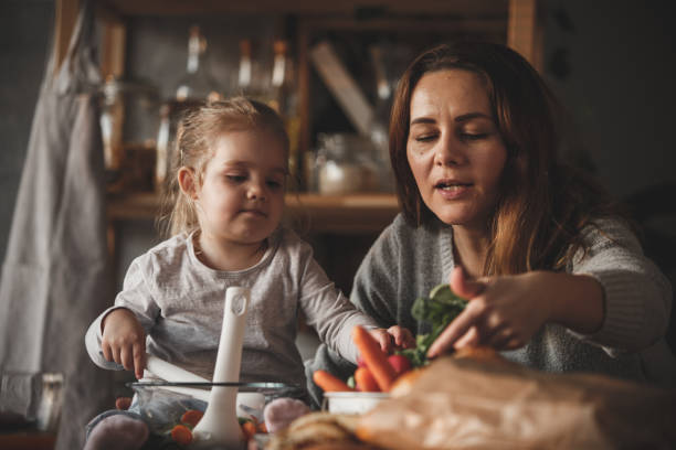 istock Mother reaching for vegetables, preparing salad with her daughter 1135709067