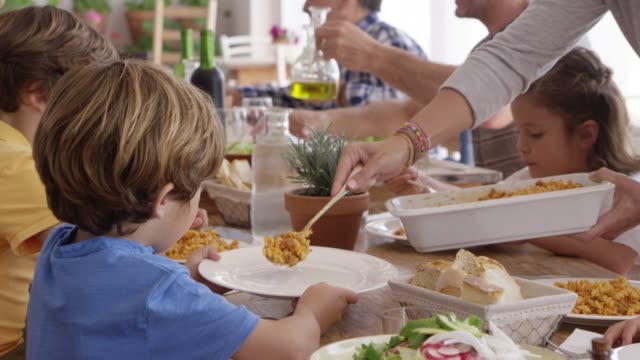 Mother serving pasta to children at dining table