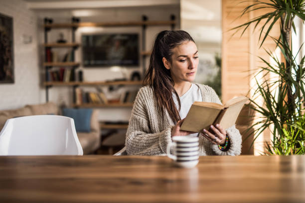 istock Young beautiful woman reading a book while relaxing at home. 1135712045