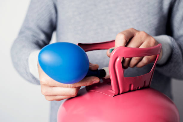 inflating a balloon with helium from a cylinder - helium imagens e fotografias de stock