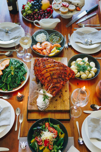 istock Modern Australian Christmas dinner table with glazed ham, prawns, potatoes and dill, asian greens, Christmas pudding, minced fruit pies by candlelight 1135713530