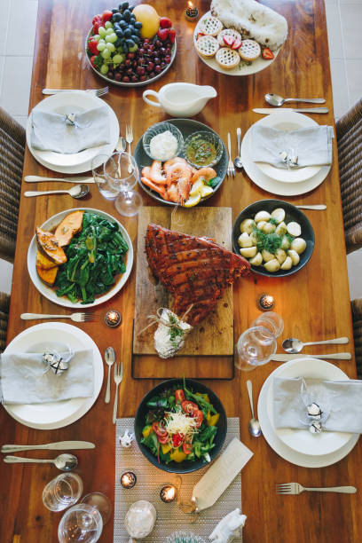 istock Modern Australian Christmas dinner table with glazed ham, prawns, potatoes and dill, asian greens, Christmas pudding, minced fruit pies by candlelight 1135713579