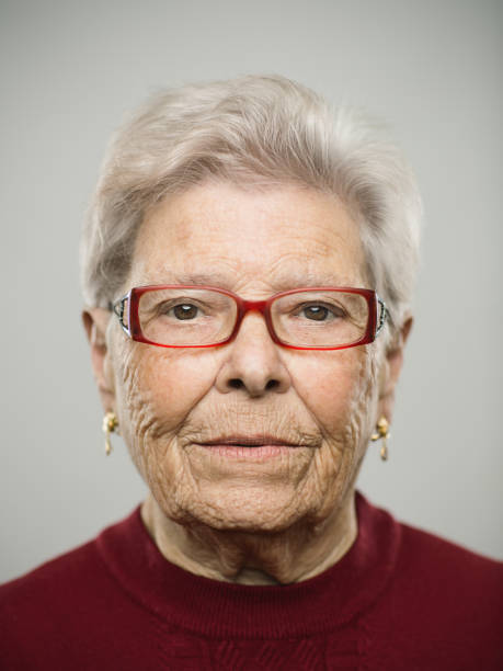 Portrait of real caucasian senior woman with blank expression Close up portrait of senior caucasian woman with blank expression against gray white background. Vertical shot of spanish real people staring in studio with white hair and glasses. Photography from a DSLR camera. Sharp focus on eyes. formal portrait photos stock pictures, royalty-free photos & images