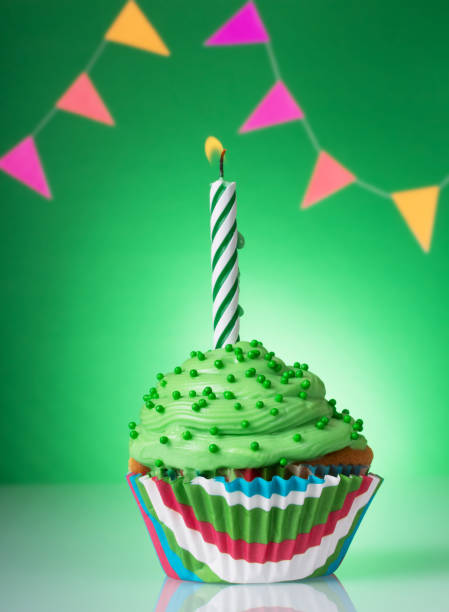 istock Festive cupcake with green cream and lighted candle on a bright background 1135723696