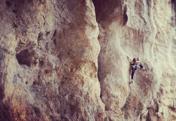 Girl rock climber climbs difficult route on the cliffs
