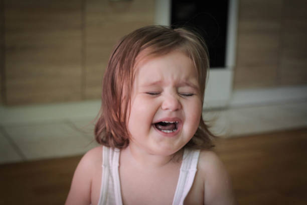 infelice bambina bionda di un anno piange miseramente. - miseramente foto e immagini stock